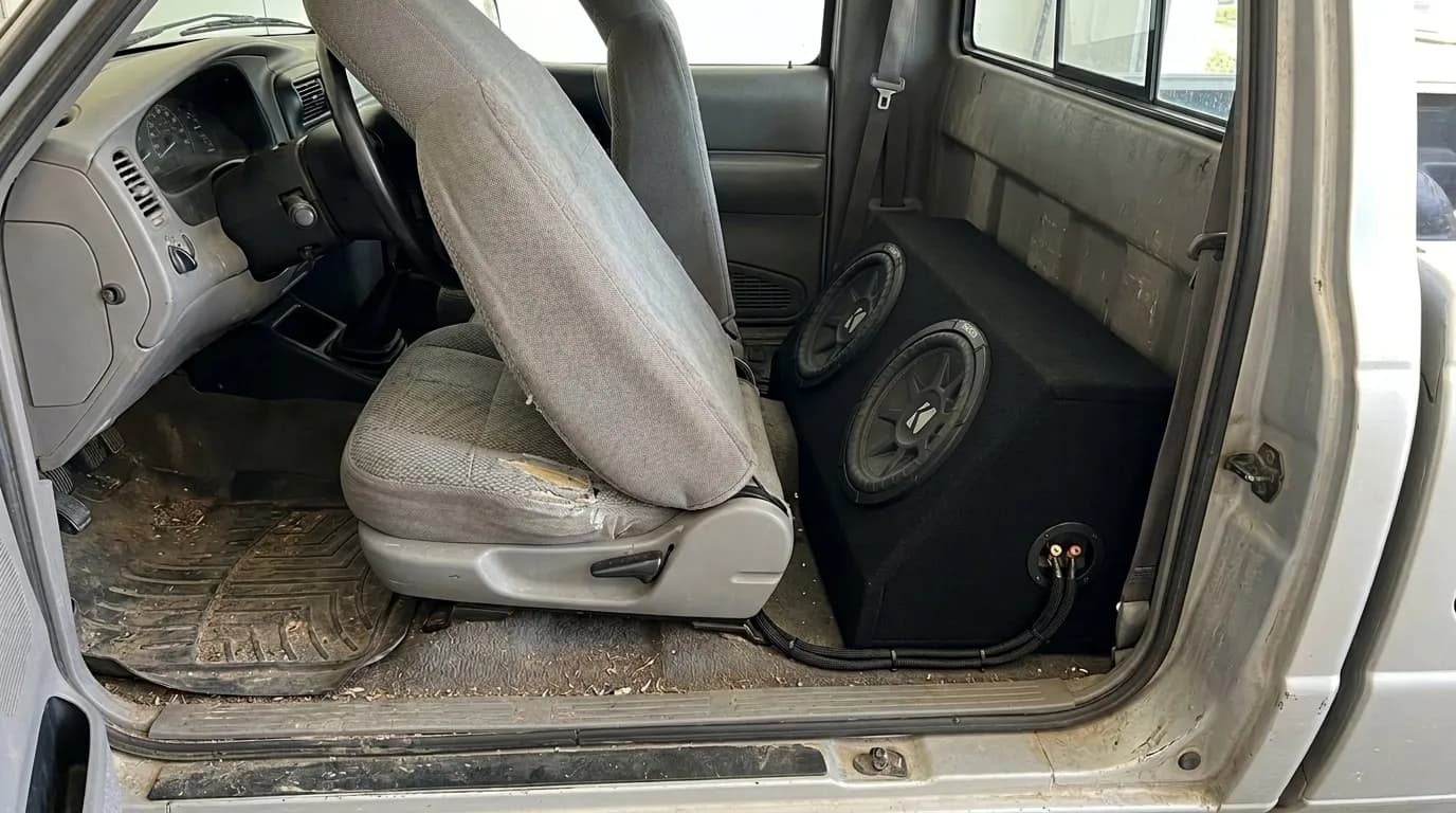 Sealed subwoofer box fitted behind the seat of a pickup truck